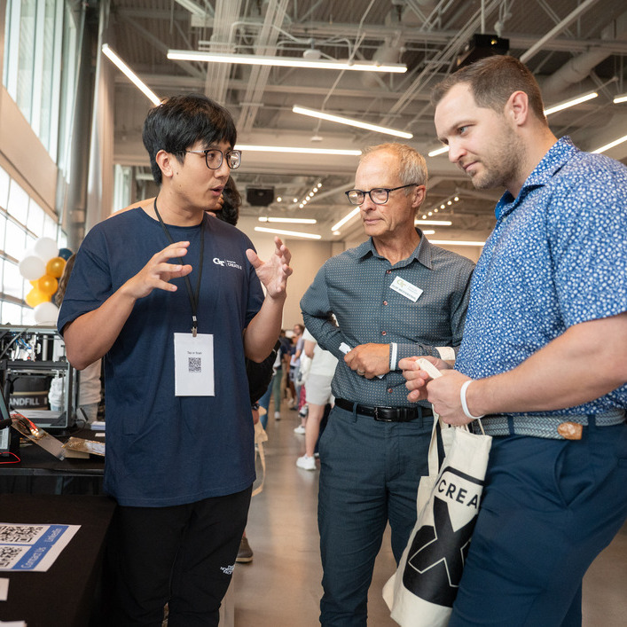 Three individuals in a discussion at a kiosk