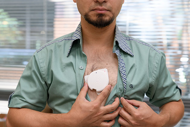 man baring chest an holding a patch against his skin