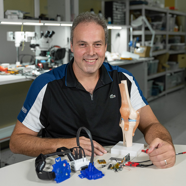 man sitting at a table in a lab with several items in front of him